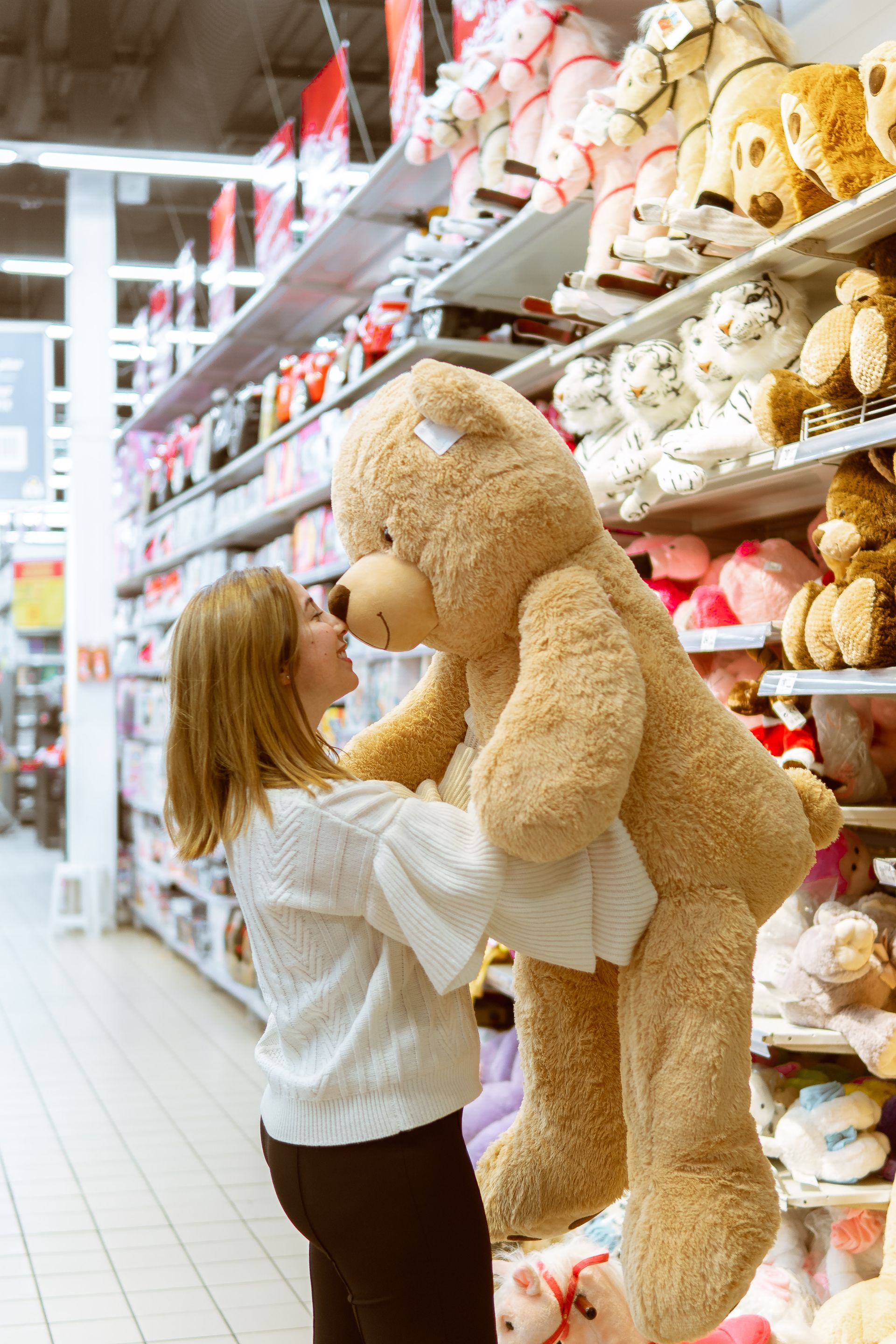 Woman Holding Large Premium Quality Teddy Bear in Toy Store with Plush Collection